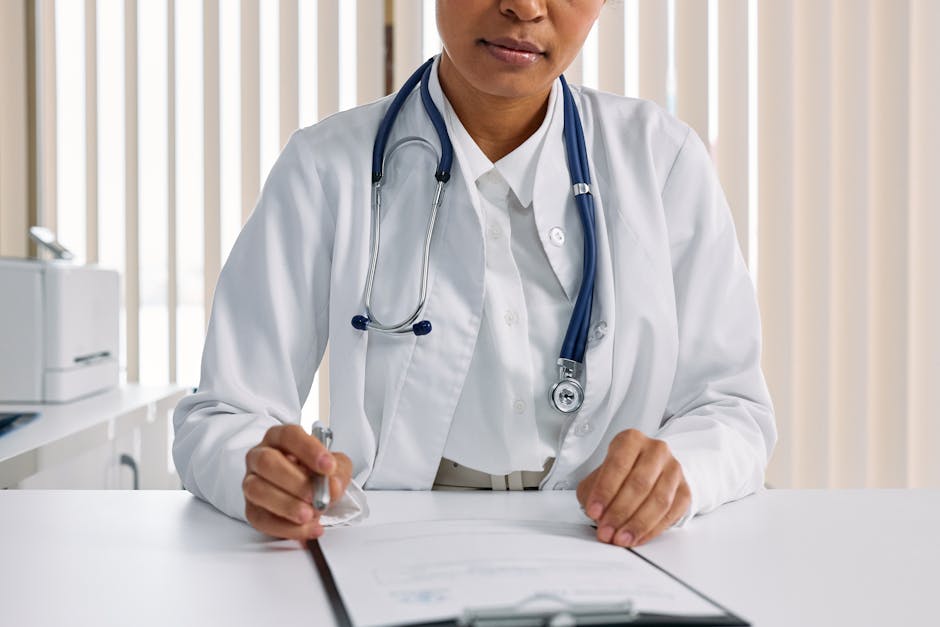 A focused doctor with stethoscope recording patient details in an office setting